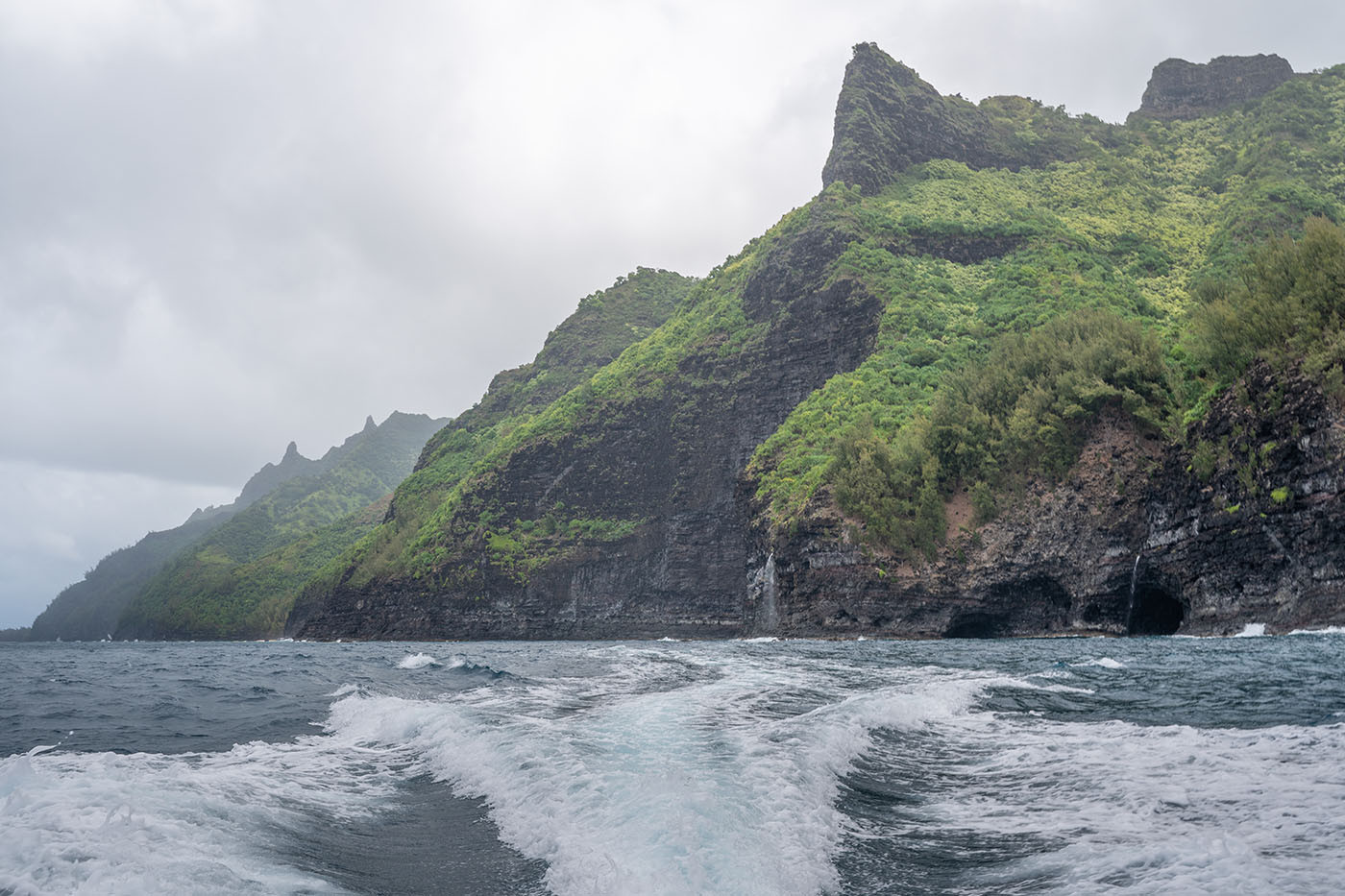 na-pali-coast-boat-tour.jpg Boat wake trailing past green sea cliffs and coastal caves