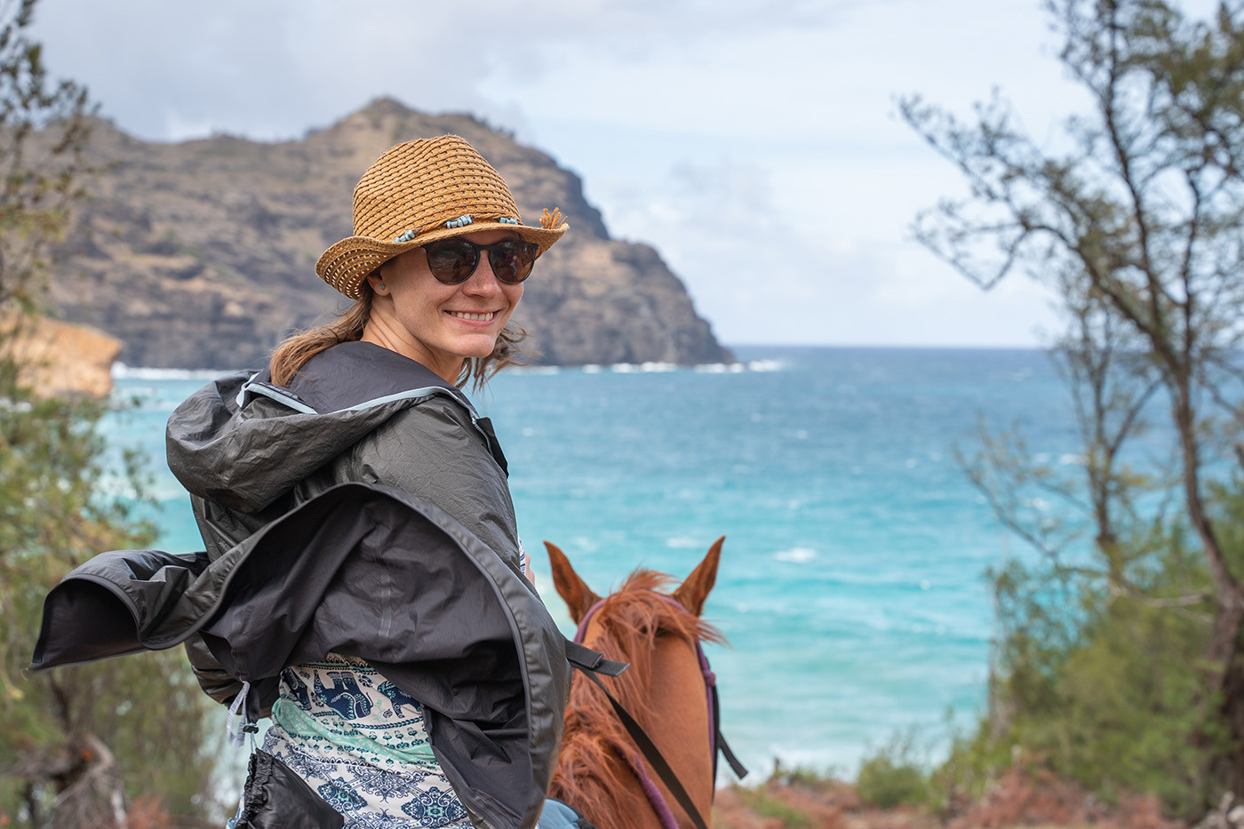 haula-beach-horseback-riding.jpg Rider smiling on horseback above turquoise Haula Bay