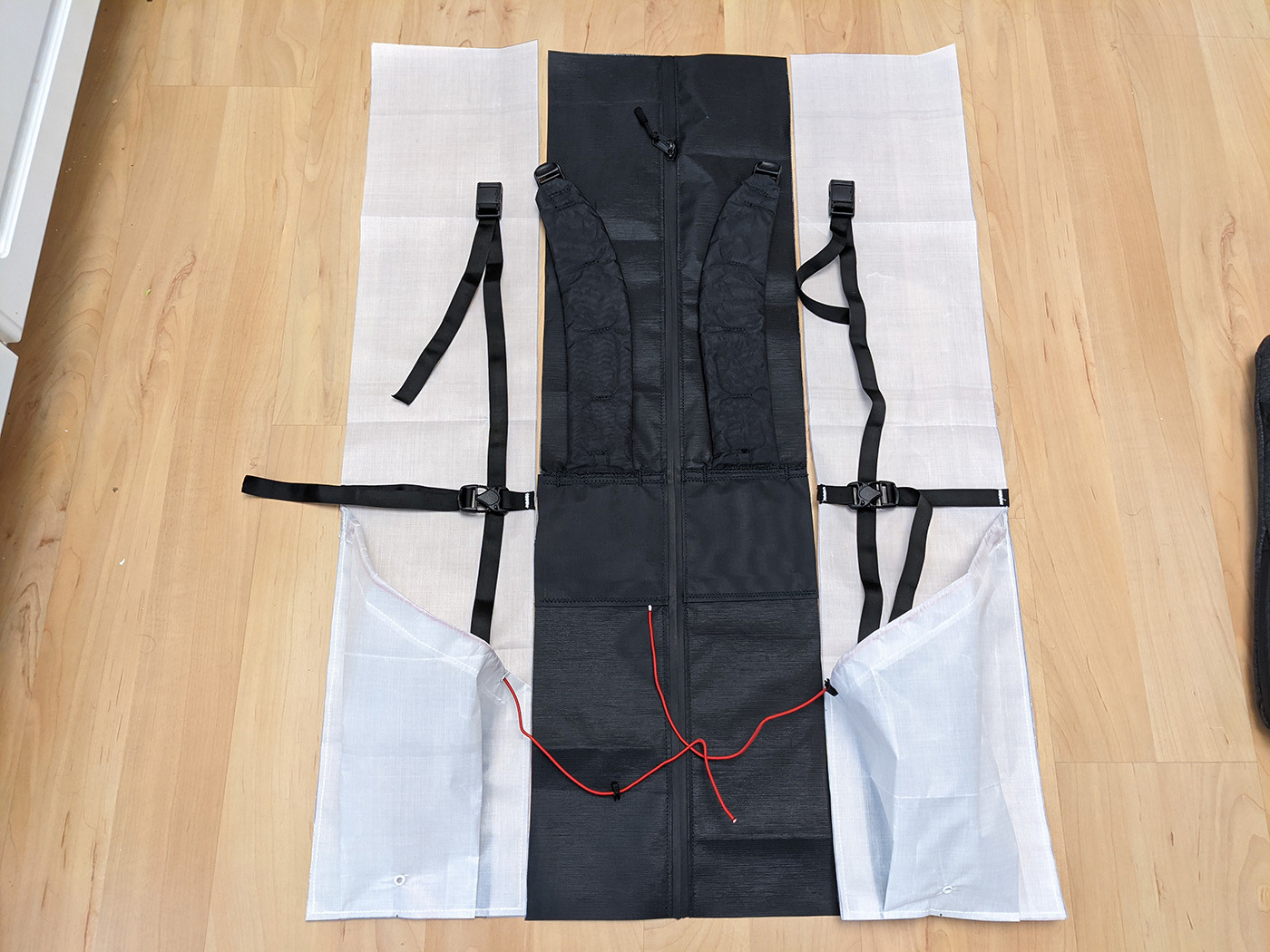 Back panel, shoulder straps, side pockets, and compression straps laid flat