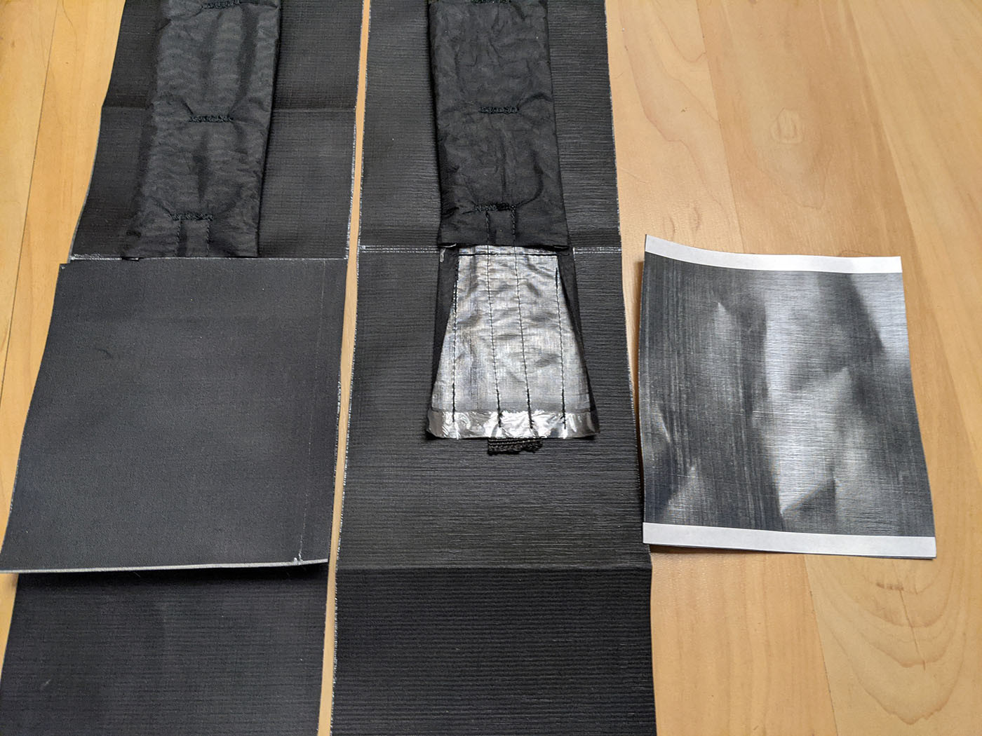 Shoulder strap padding, webbing, and fabric layers laid out for assembly