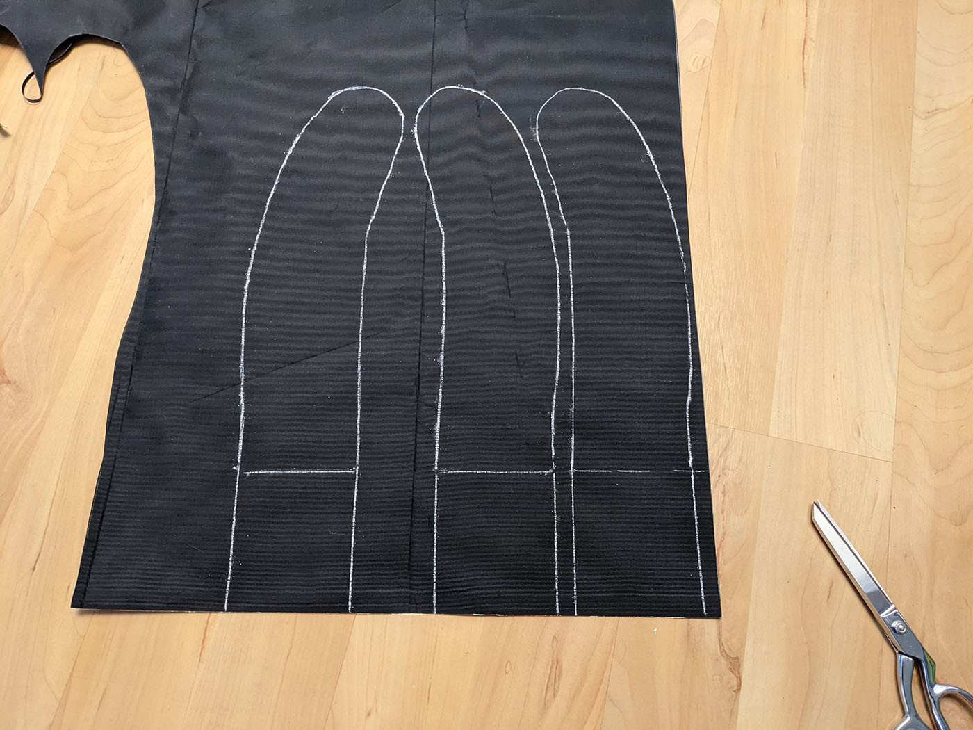 Three shoulder strap patterns traced in chalk on black fabric