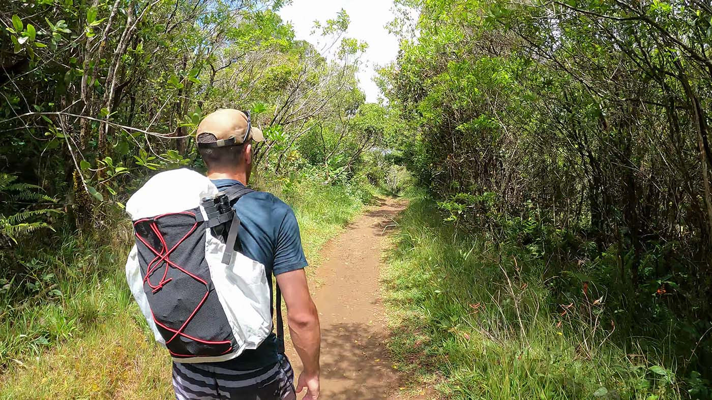 Hiker testing the homemade Dyneema backpack on a leafy trail