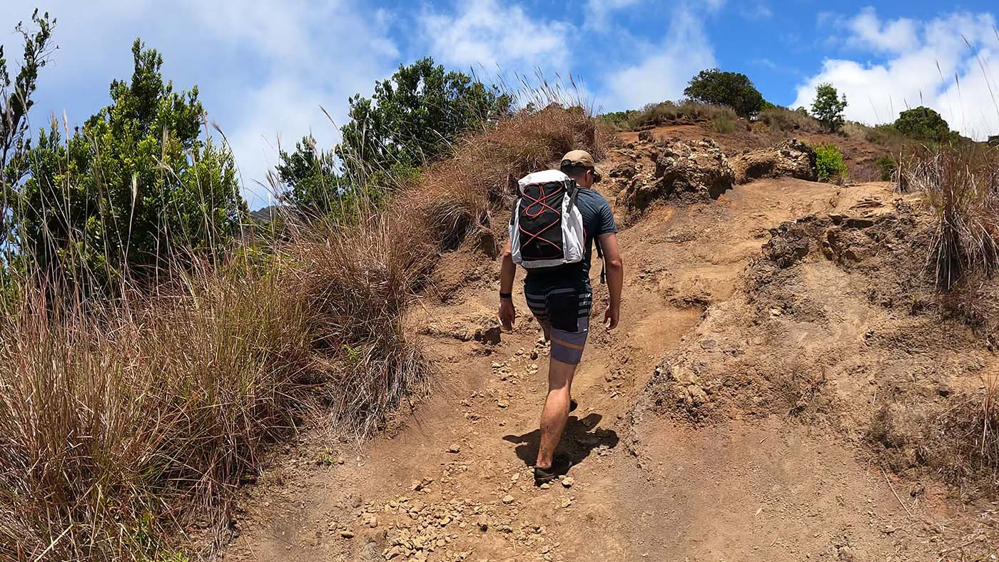 Hiker carrying the homemade backpack up a steep rocky trail