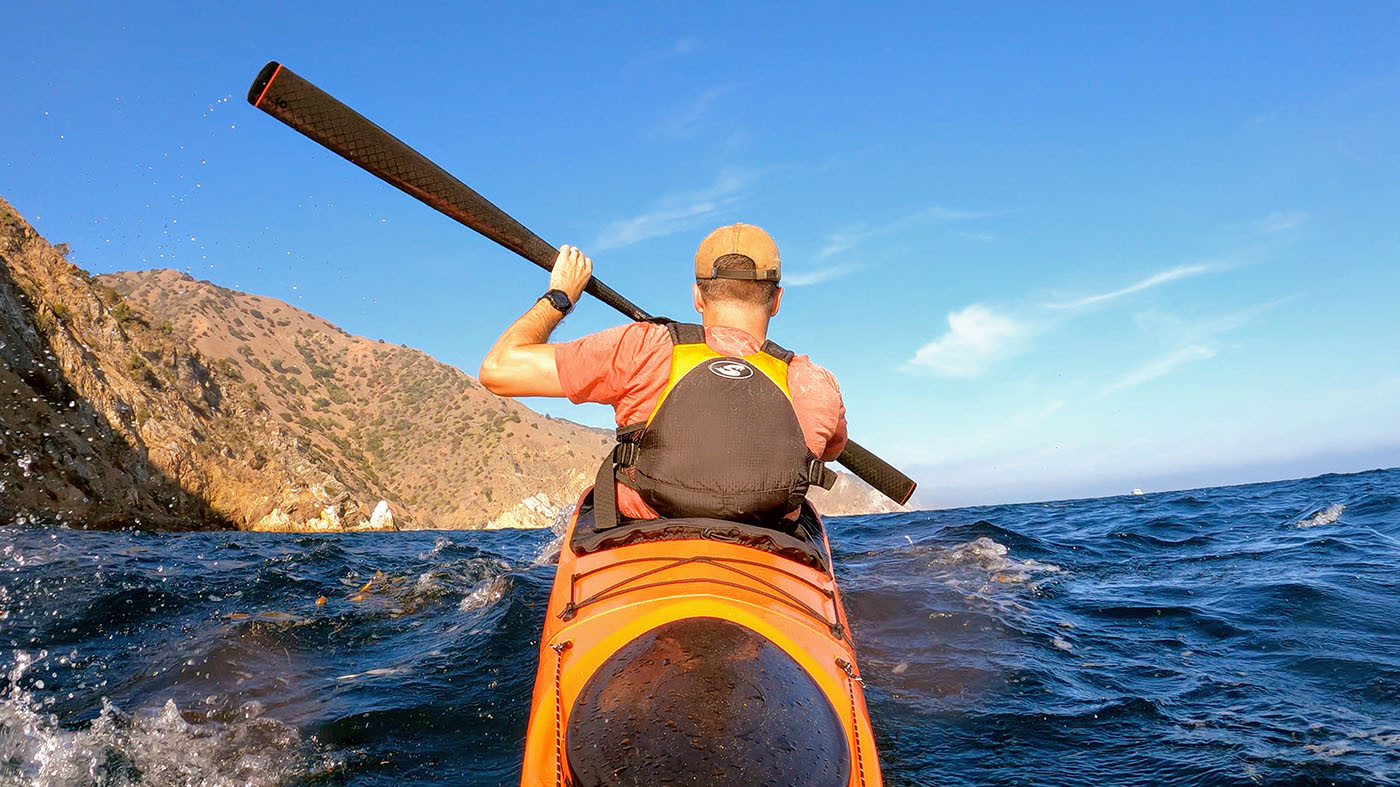Kayaker paddling an orange Pakayak through rolling waves off Catalina Island