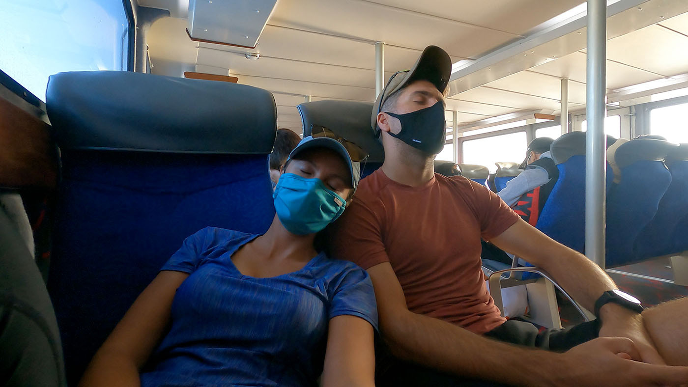 Two masked kayakers napping together on the Catalina ferry