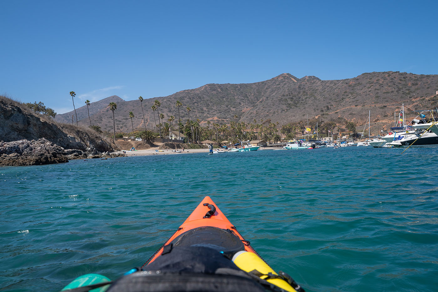 View from an orange kayak approaching the beach and marina at Two Harbors