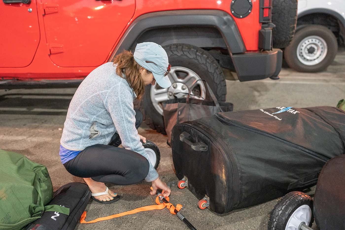 Securing custom large wheels to a Pakayak travel bag beside a Jeep