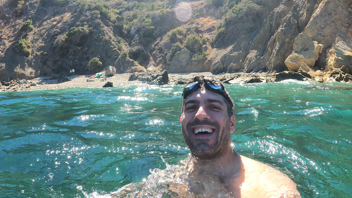 Swimmer smiling in the turquoise water below the Italian Gardens campsite